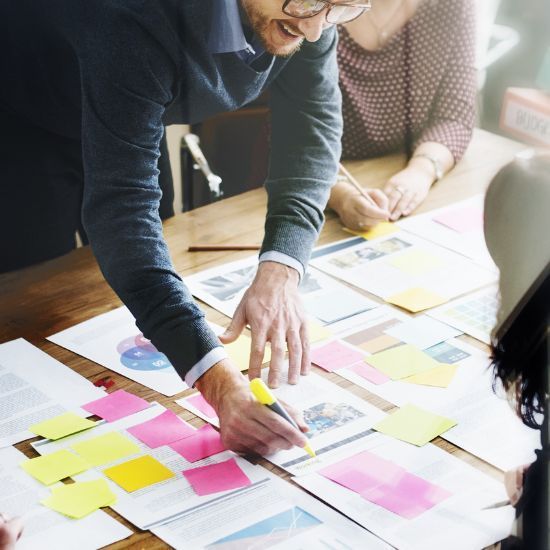 a group of people are sitting around a table with sticky notes on it planning for marketing