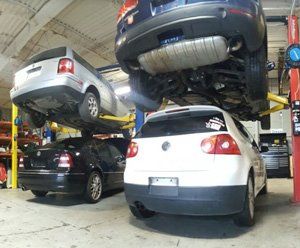 Three cars are sitting on lifts in a garage