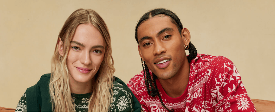 A man and a woman are posing for a picture while wearing christmas sweaters.