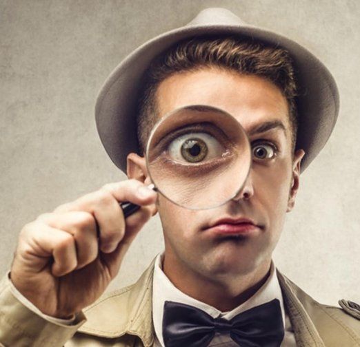 A man in a hat and bow tie is looking through a magnifying glass