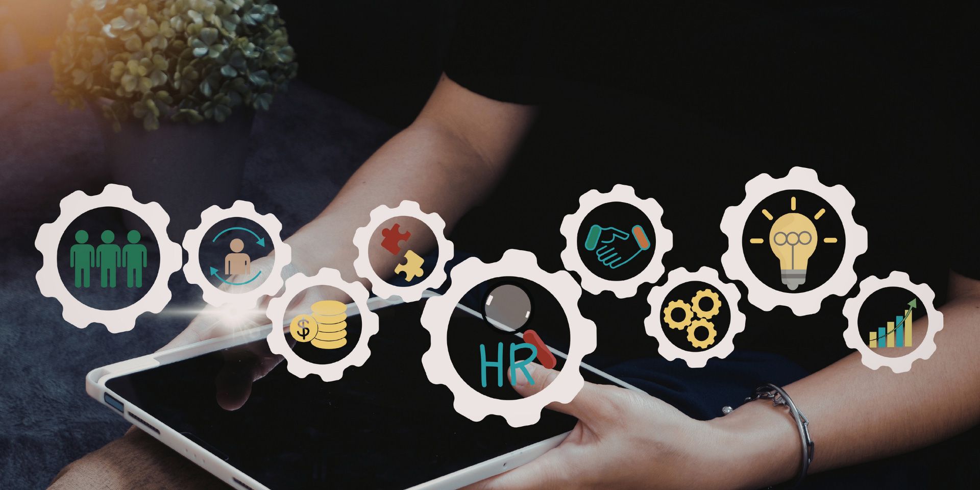 Hands using a tablet with floating gear icons for teamwork, data, and business automation