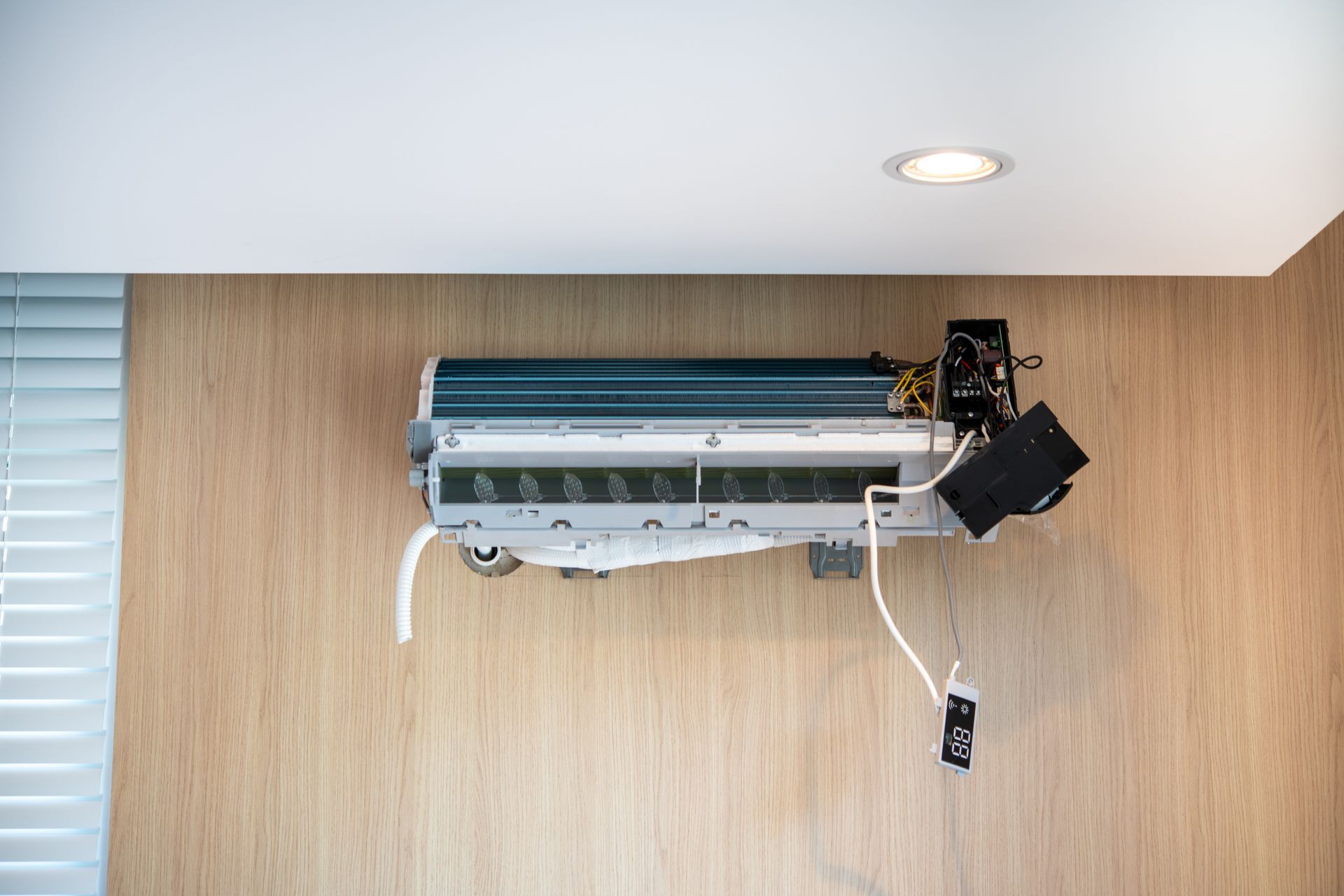 Wall-mounted air conditioner unit on a wood-paneled wall beneath a ceiling light