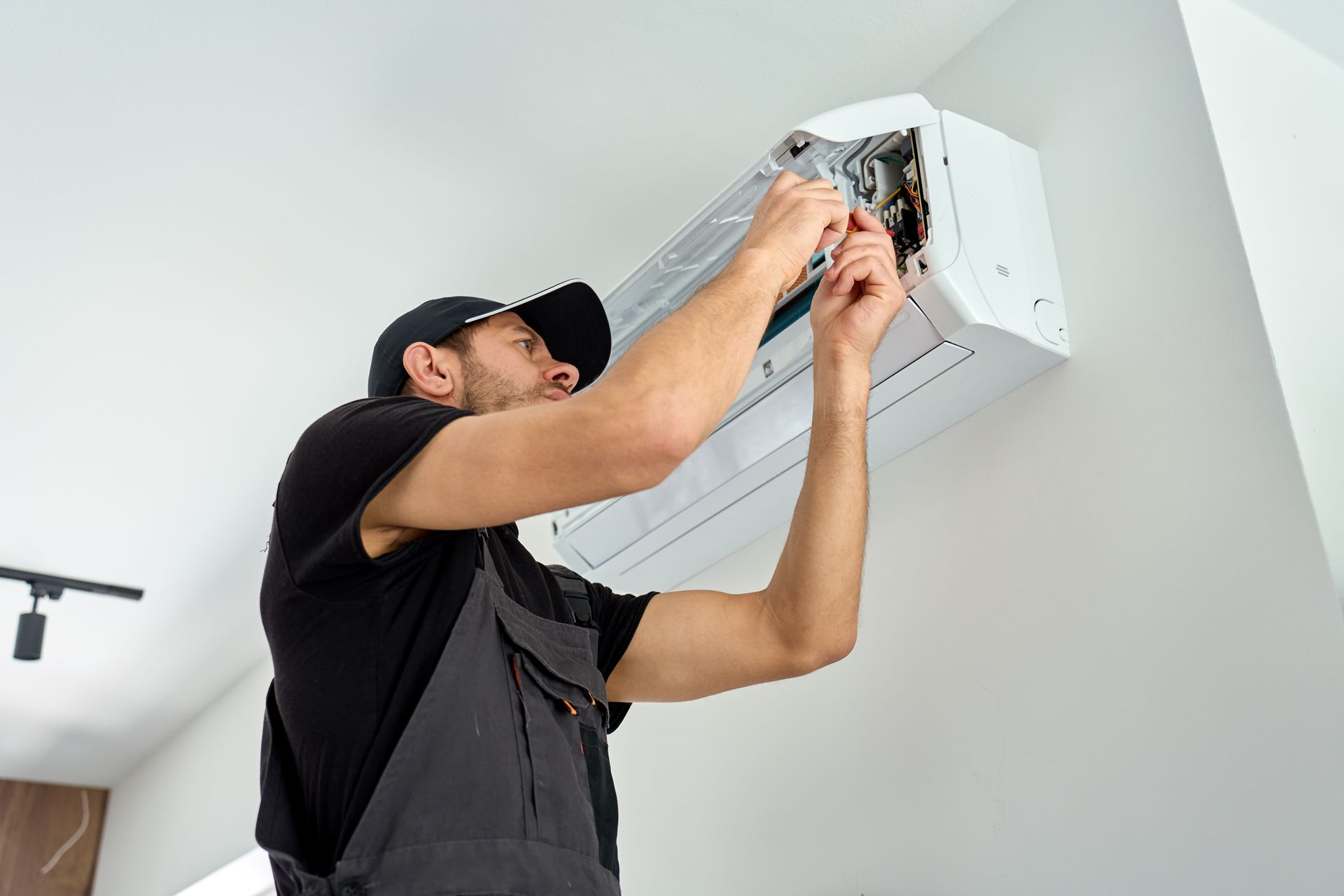 Technician repairing a wall-mounted air conditioner indoors with tools