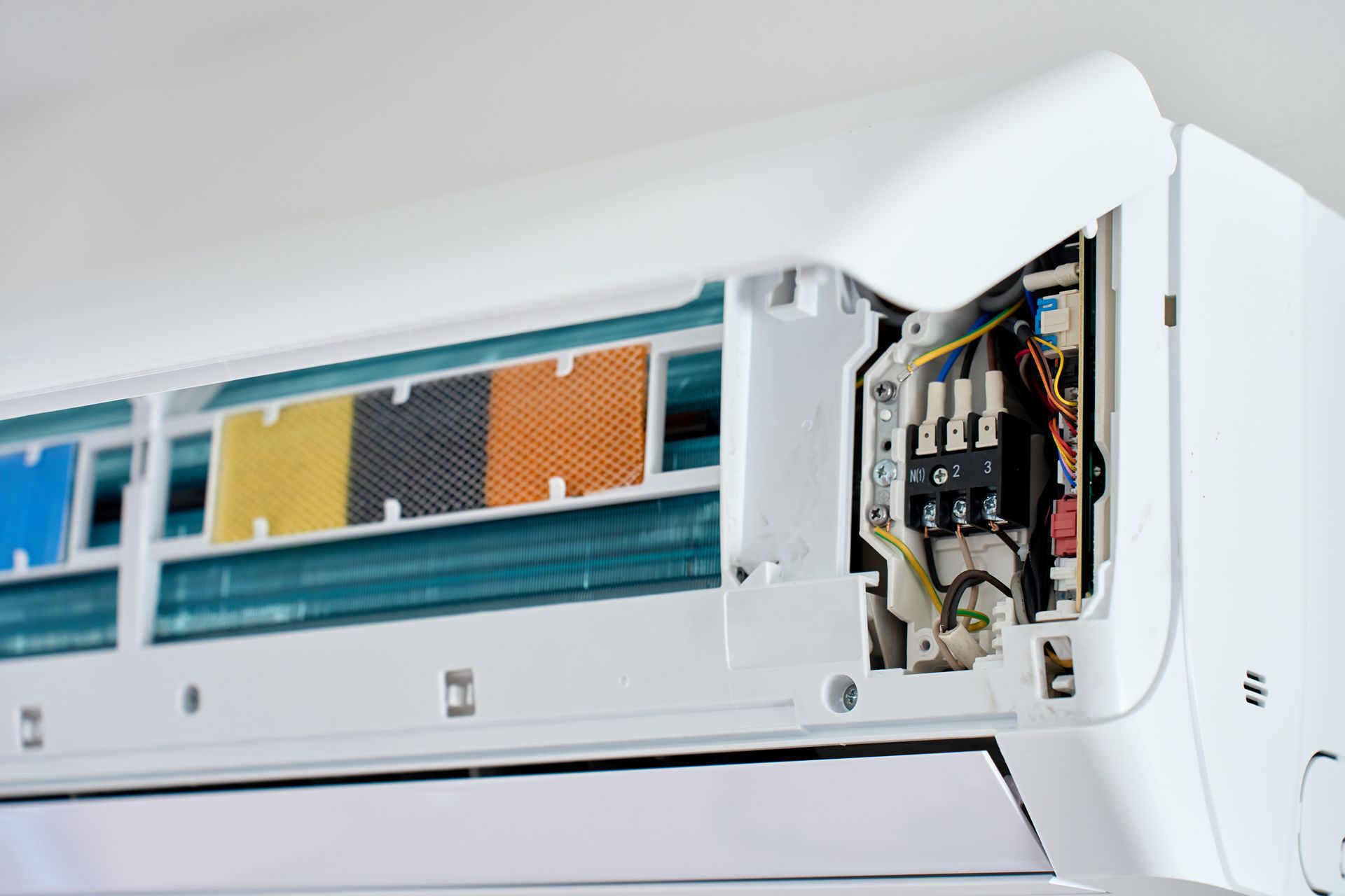 Wall-mounted air conditioner with open front panel revealing internal filters and wiring