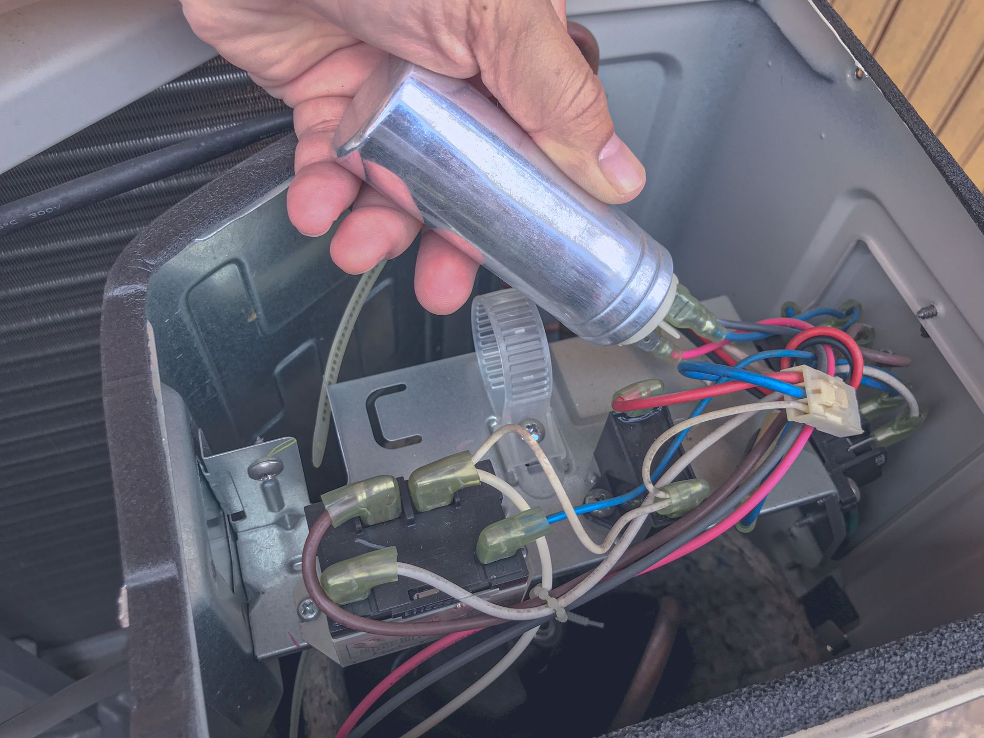 Hand holding a flashlight over exposed wiring and components inside a car dashboard cavity