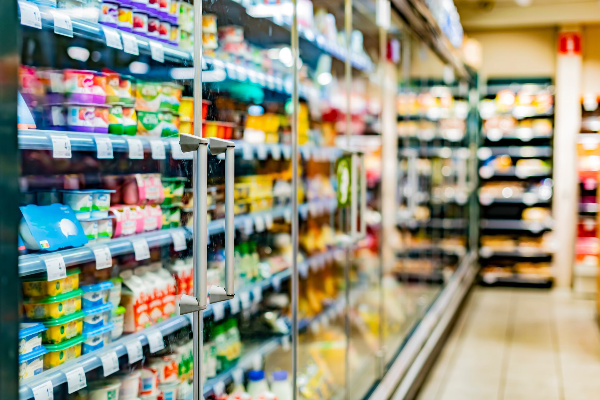 Grocery store aisle with shelves stocked with colorful packaged goods and bright blurred lights