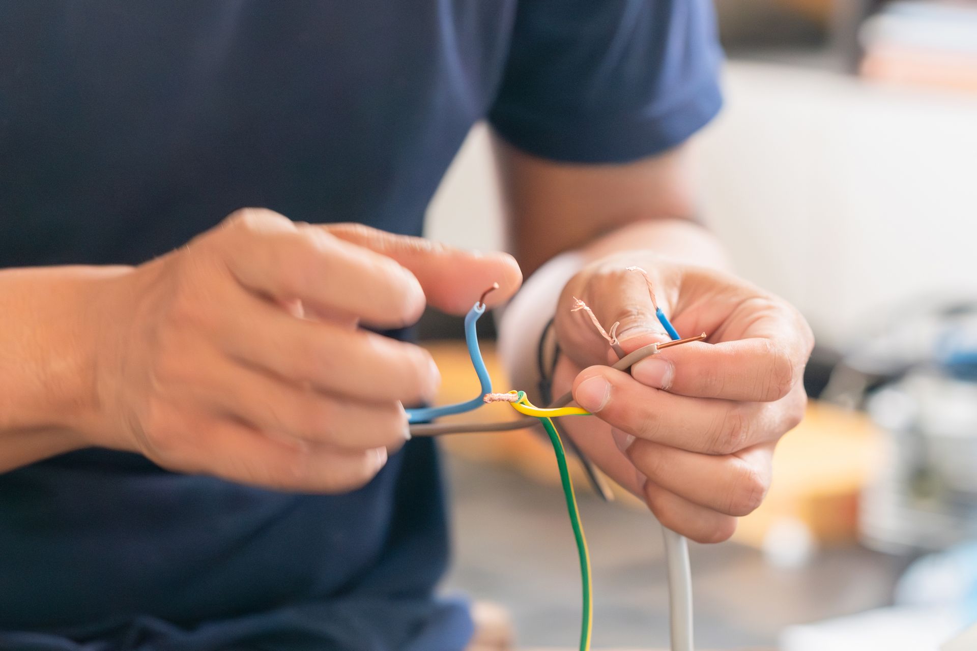 Hands twisting multicolored wires together on a workbench