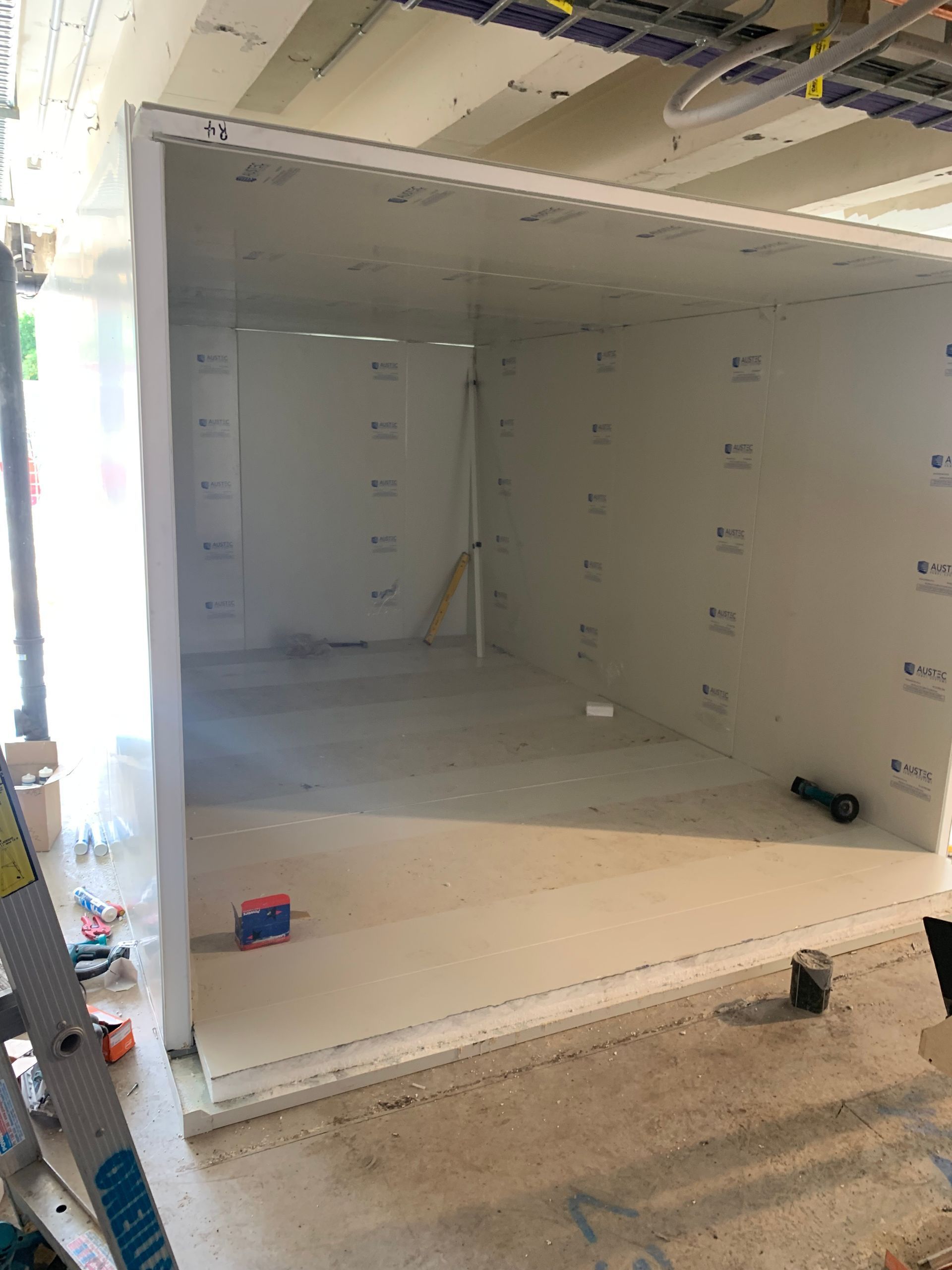 Unfinished room under construction with exposed insulation, drywall, and tools on the floor