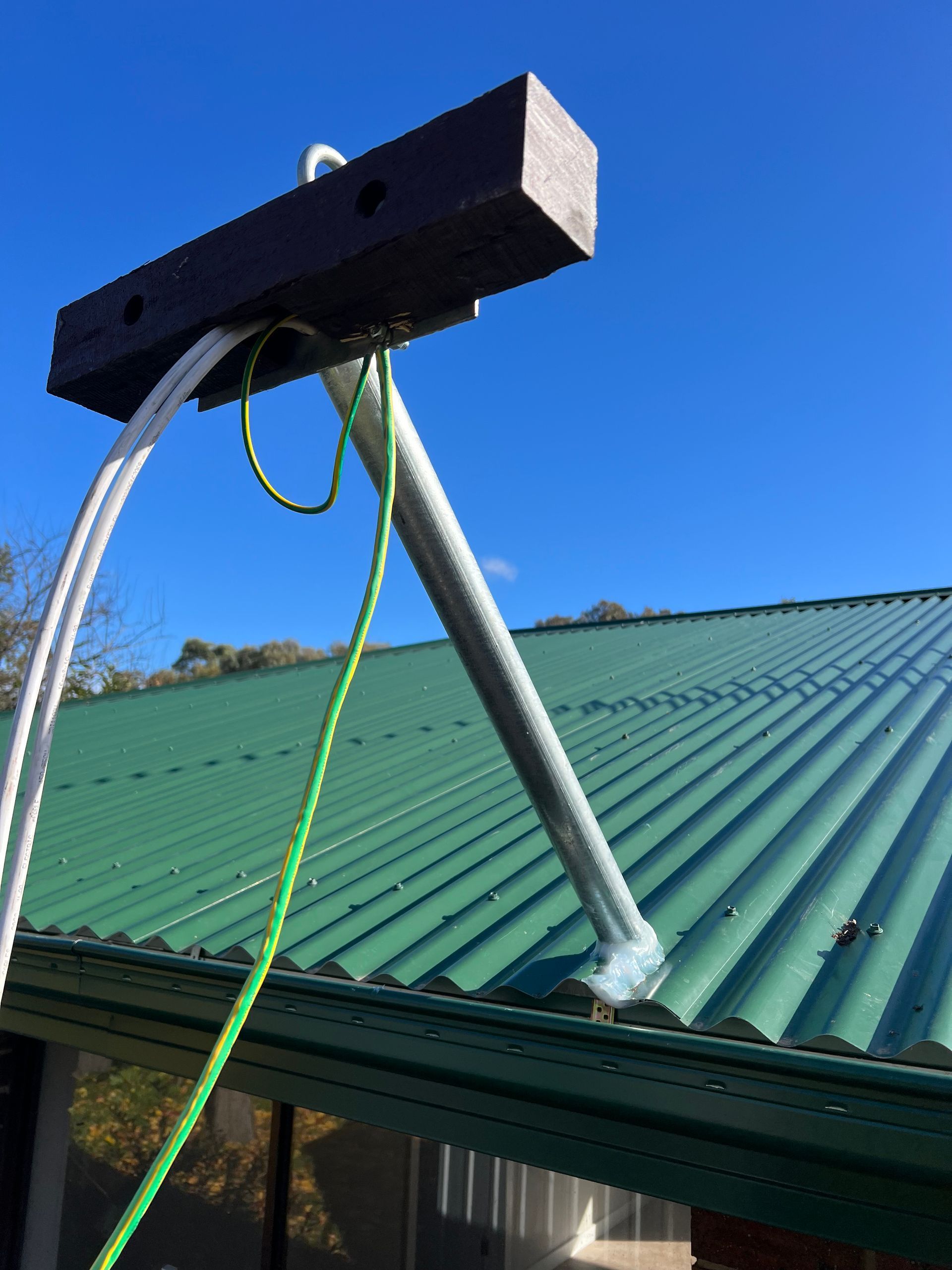 Metal roof with a tripod stand and green rope against a blue sky