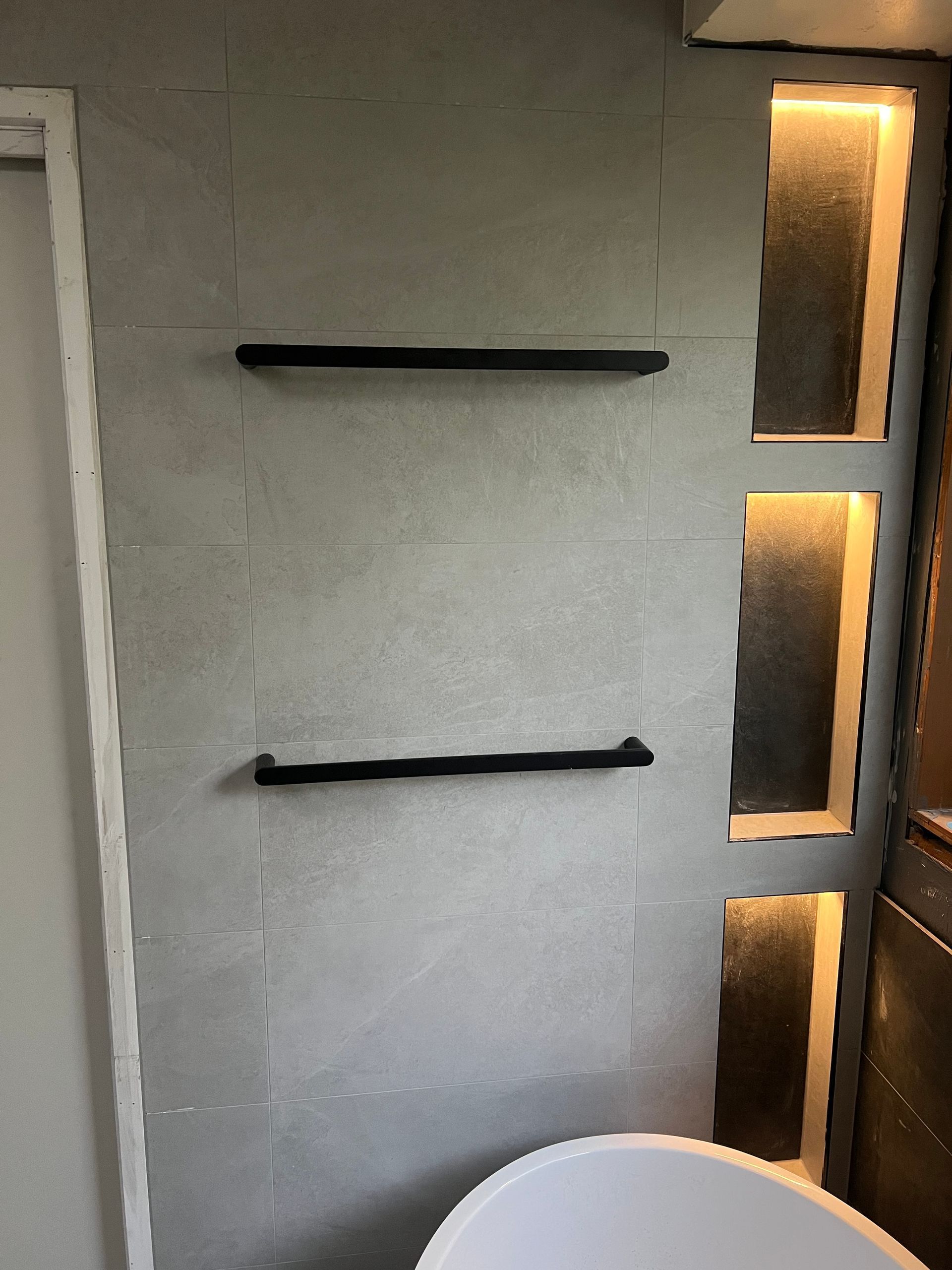 Interior wall with two black shelves and vertical frosted glass light panels on the right