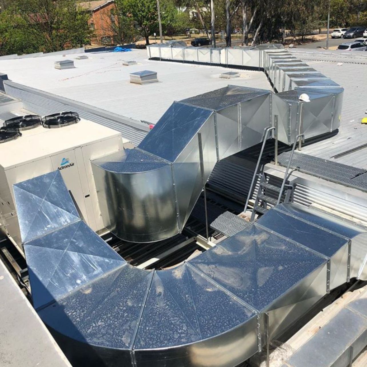 Rooftop HVAC ductwork and metal vents on a white commercial roof