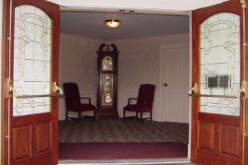 Open double doors into a small room with two chairs and a grandfather clock