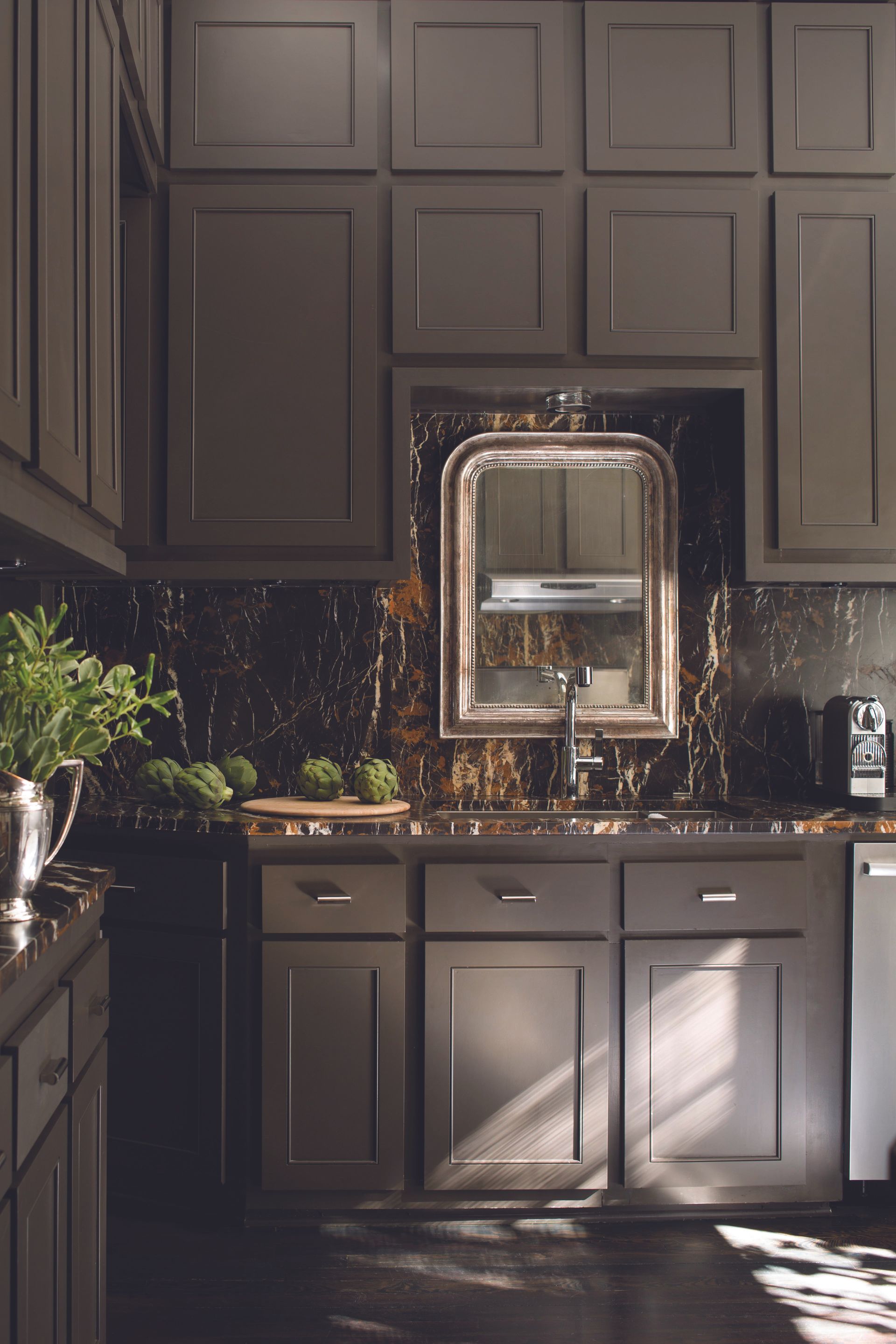 A kitchen with gray cabinets and a large mirror on the wall.