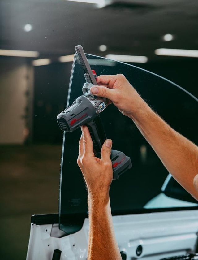 A man is cleaning the wheel of a black car with a sponge.
