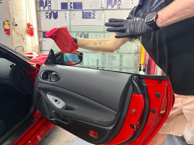 Car door panel removed during repair, with a mechanic’s gloved hands working inside the red car.
