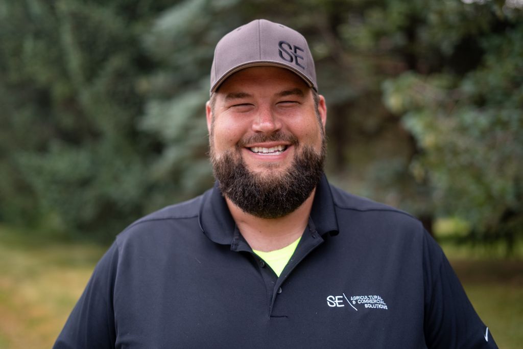 Smiling person with a beard and a gray cap with