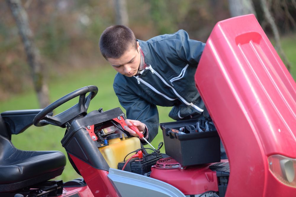 A Man Is Working On A Lawn Mower With A Screwdriver — Somerset Ride-On Mower Repairs In Kilcoy, QLD