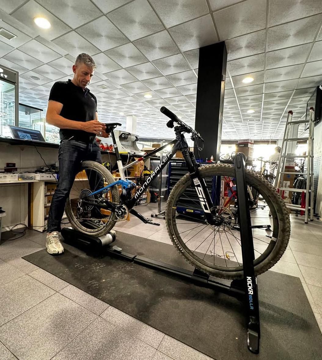 Hombre usando una tableta mientras está en una bicicleta estática en una tienda.