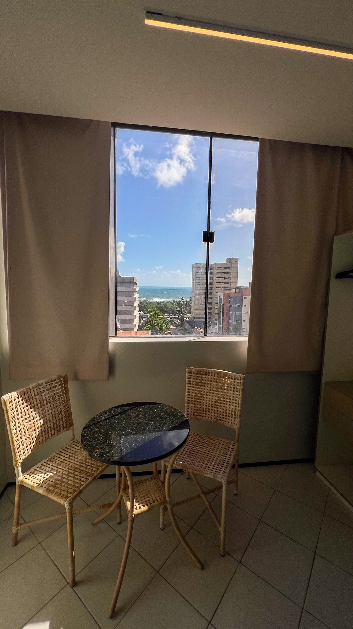 Um homem está de pé atrás de um balcão em uma sala com uma grande janela.-Boreas-Apart-Hotel