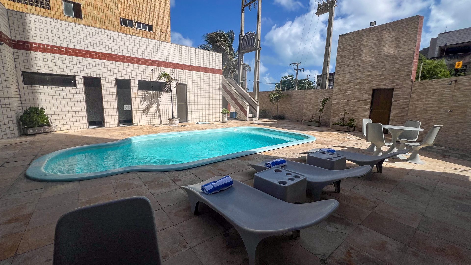 Há uma grande piscina no quintal de um prédio.-Boreas-Apart-Hotel