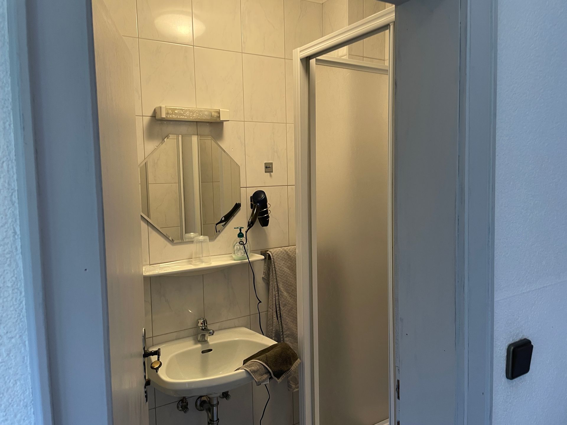 Een badkamer met wastafel, spiegel en douche.
