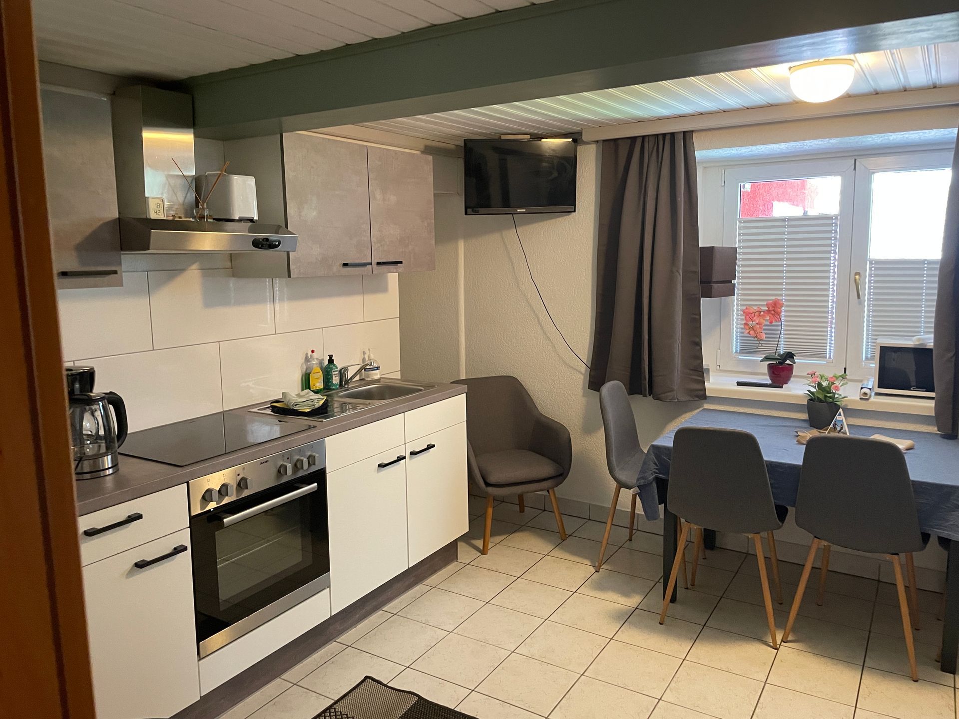 Een keuken met een tafel en stoelen en een televisie aan de muur