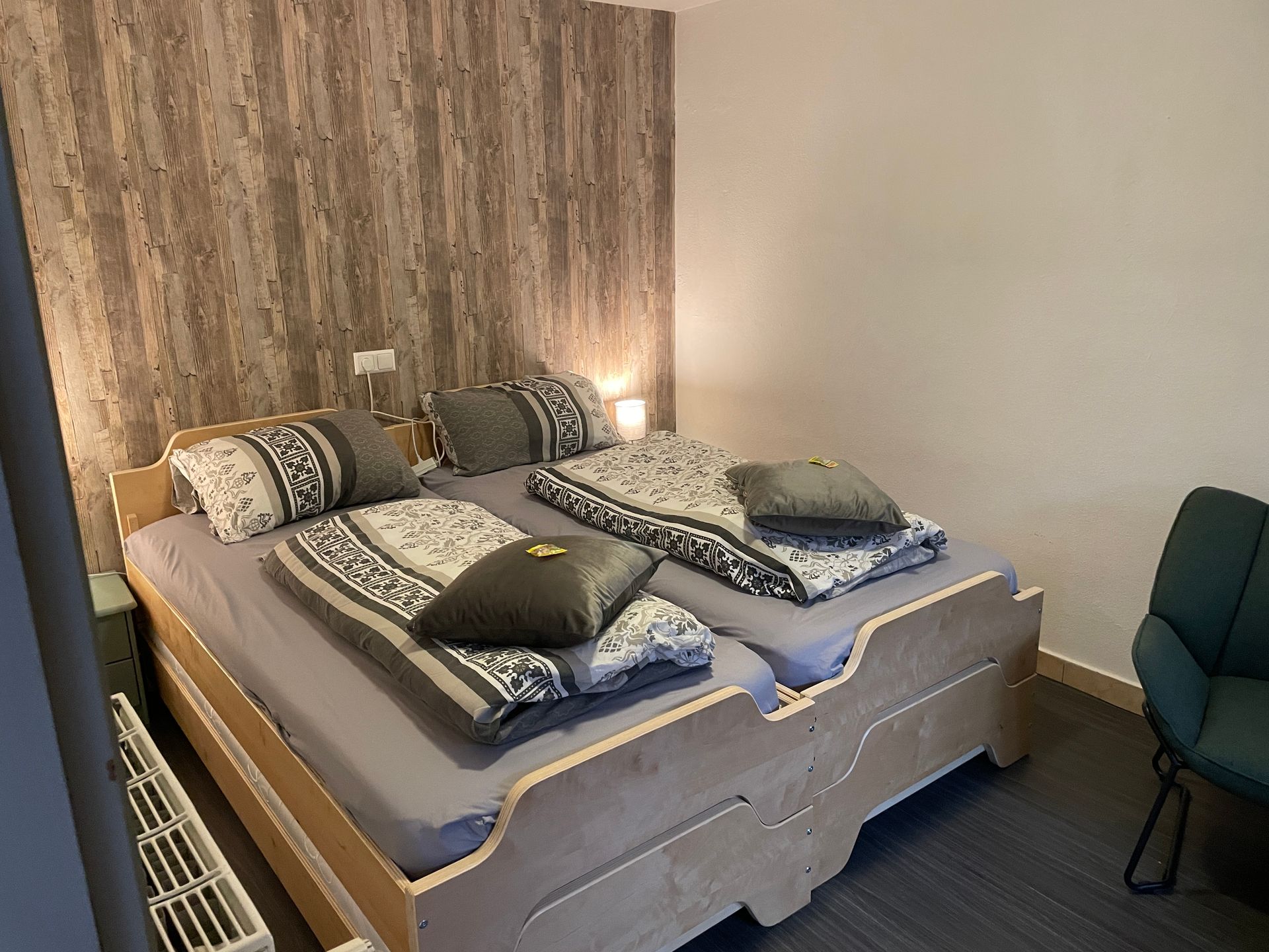 Een slaapkamer met twee bedden, een stoel en een radiator.