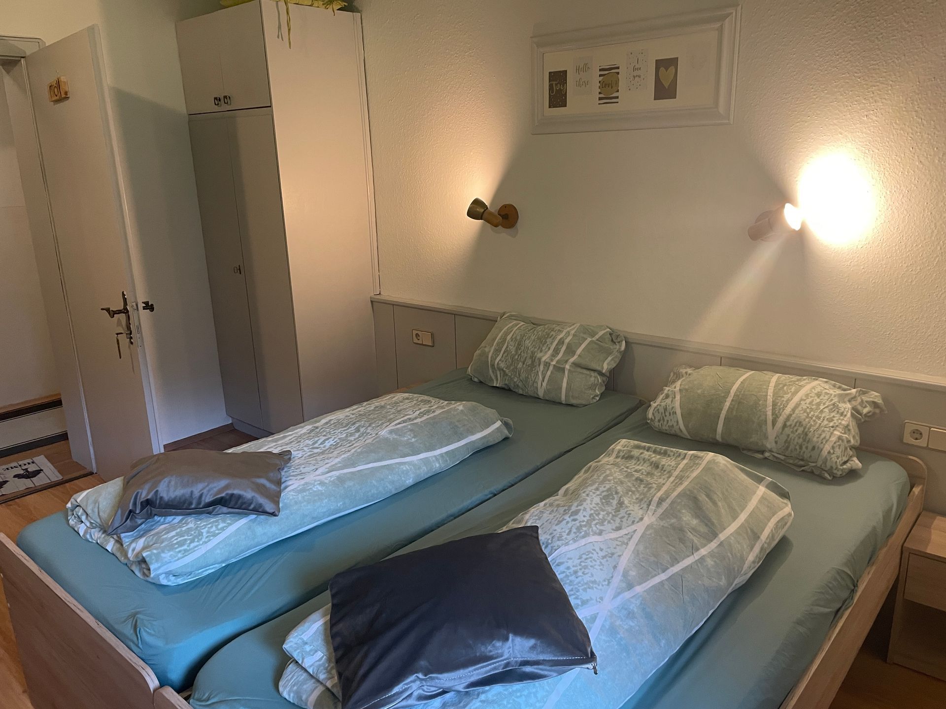 Twee bedden met blauwe lakens en kussens in een slaapkamer.