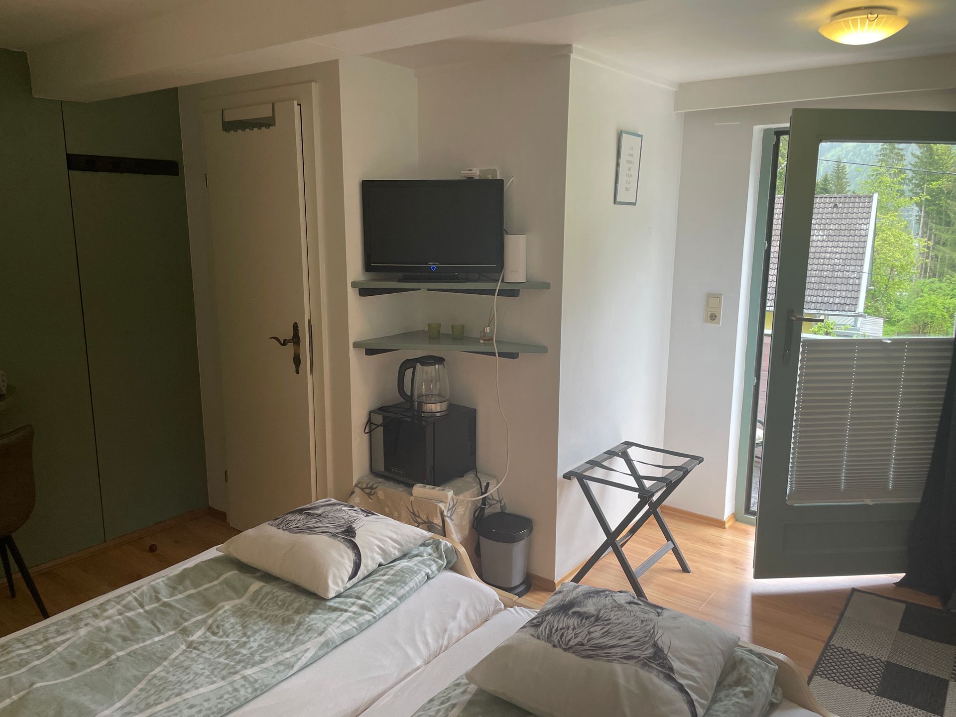 Een slaapkamer met een bed, televisie en een balkon.