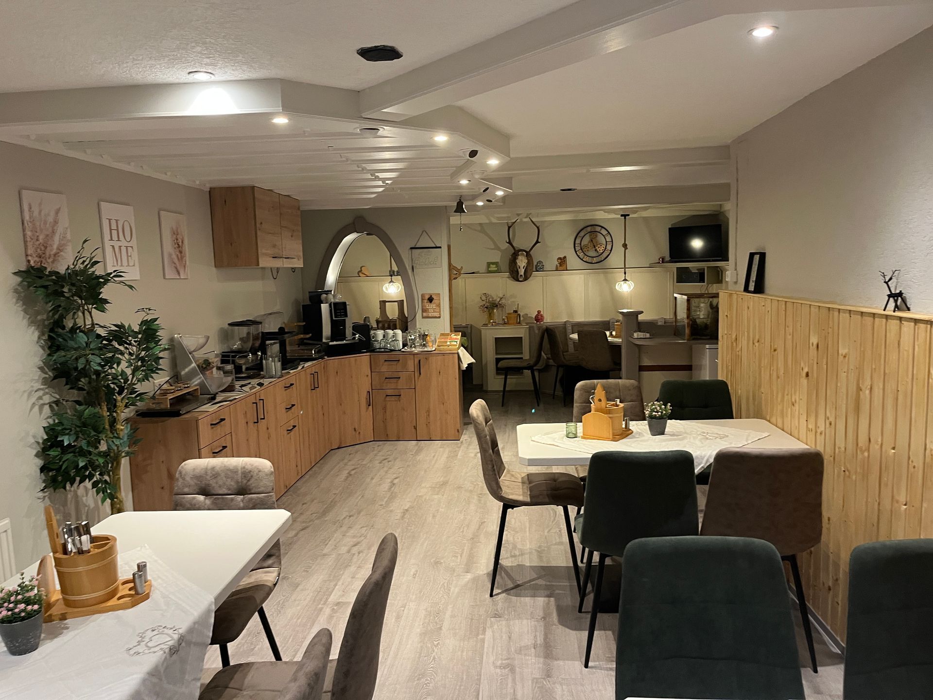 Interieur eines Cafés mit hellen Holzvertäfelungen, Tischen, Stühlen und Dekoration.