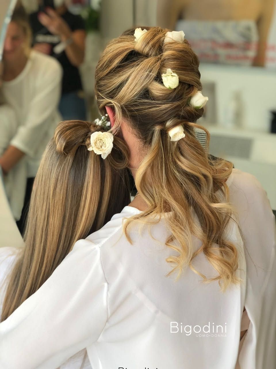 Donna che si fa truccare gli occhi, riflessa in uno specchio, con la tavolozza del trucco in primo piano.