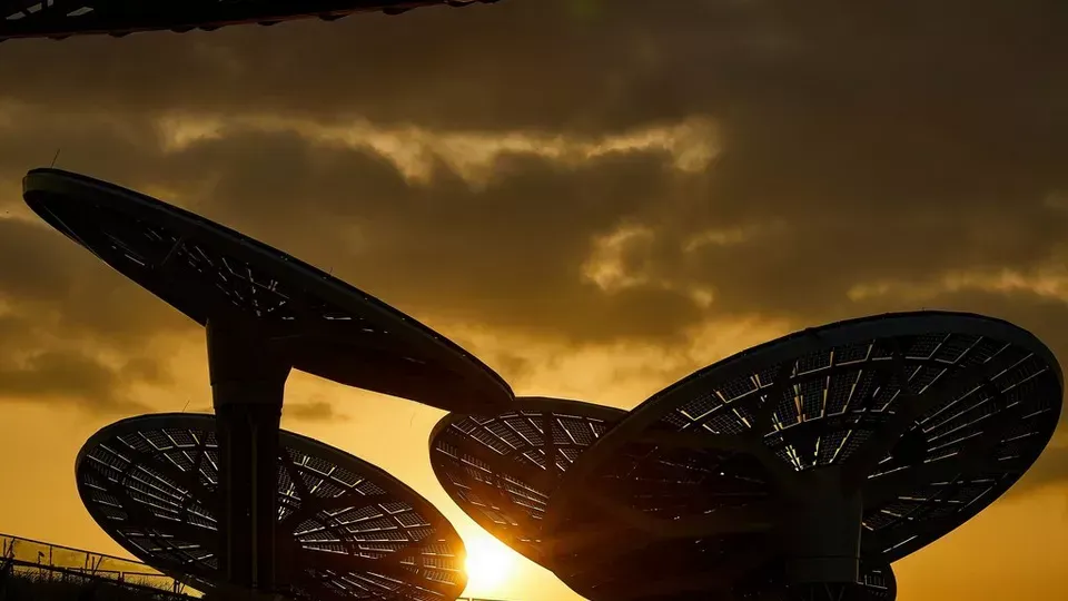 The sun is shining through the umbrellas at sunset.