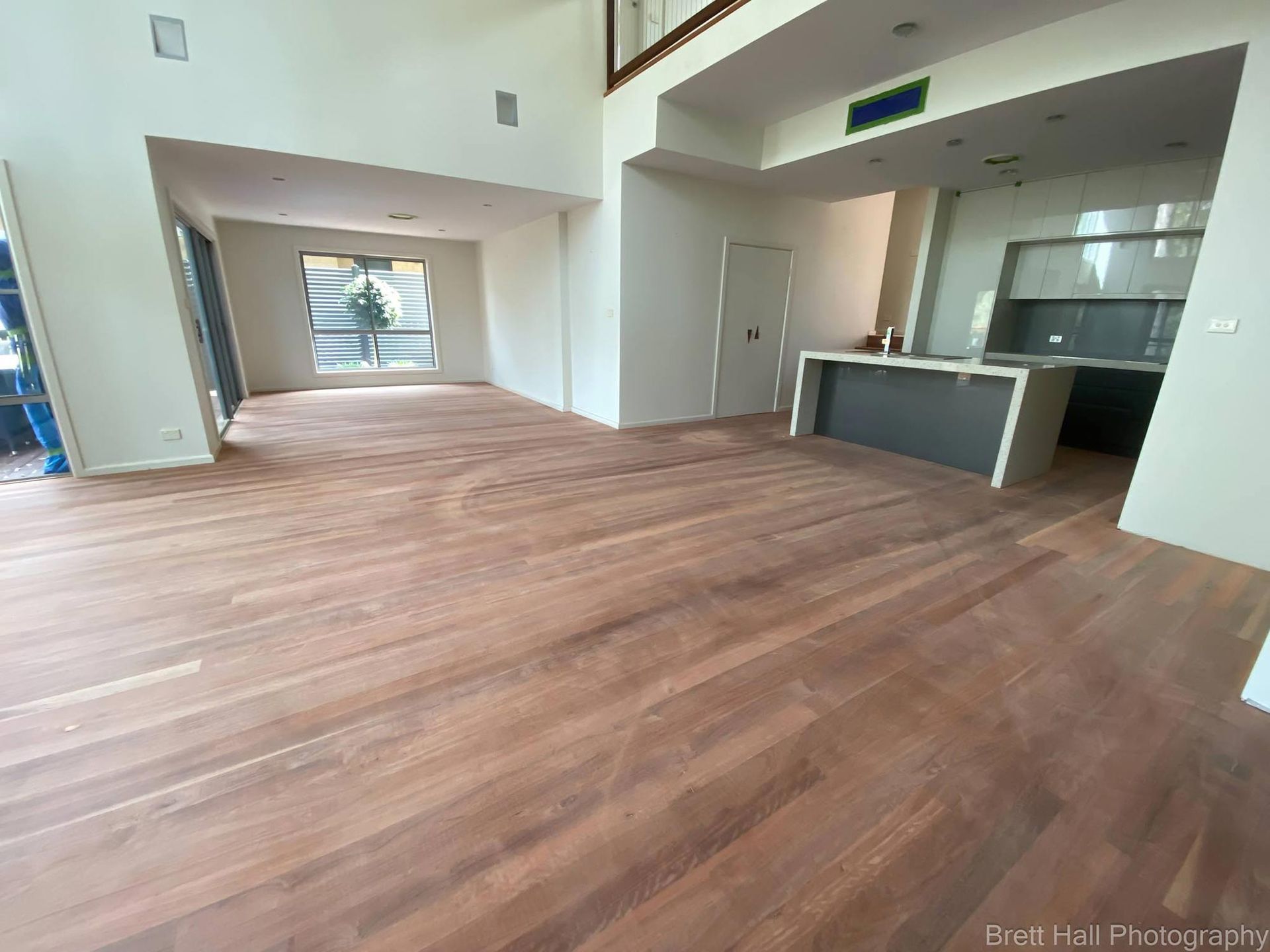 A Living Room With Sanded Hardwood Floors And A Kitchen In The Background — Brett Hall Floorsanding in Wauchope, NSW