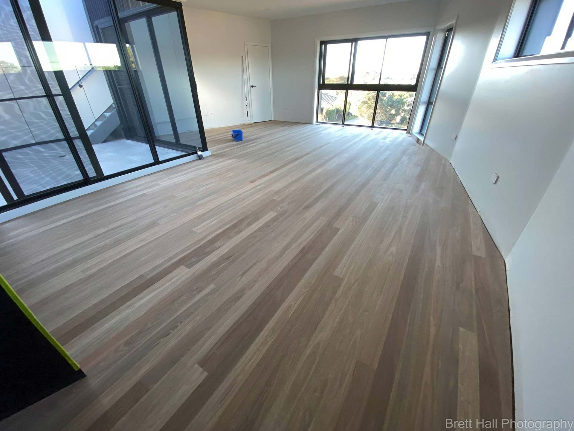 A Large Room With A Wooden Floor And Lots Of Windows — Brett Hall Floorsanding in Port Macquarie, NSW