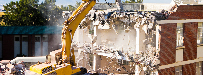 An MP Environmental Services excavator is demolishing a brick building.