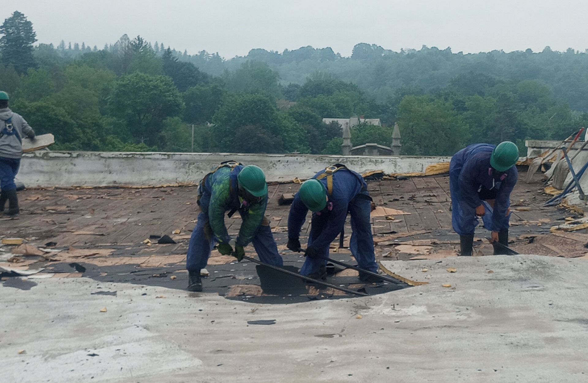 Three MP Environmental Services Inc crew members removing hazardous materials from a roof