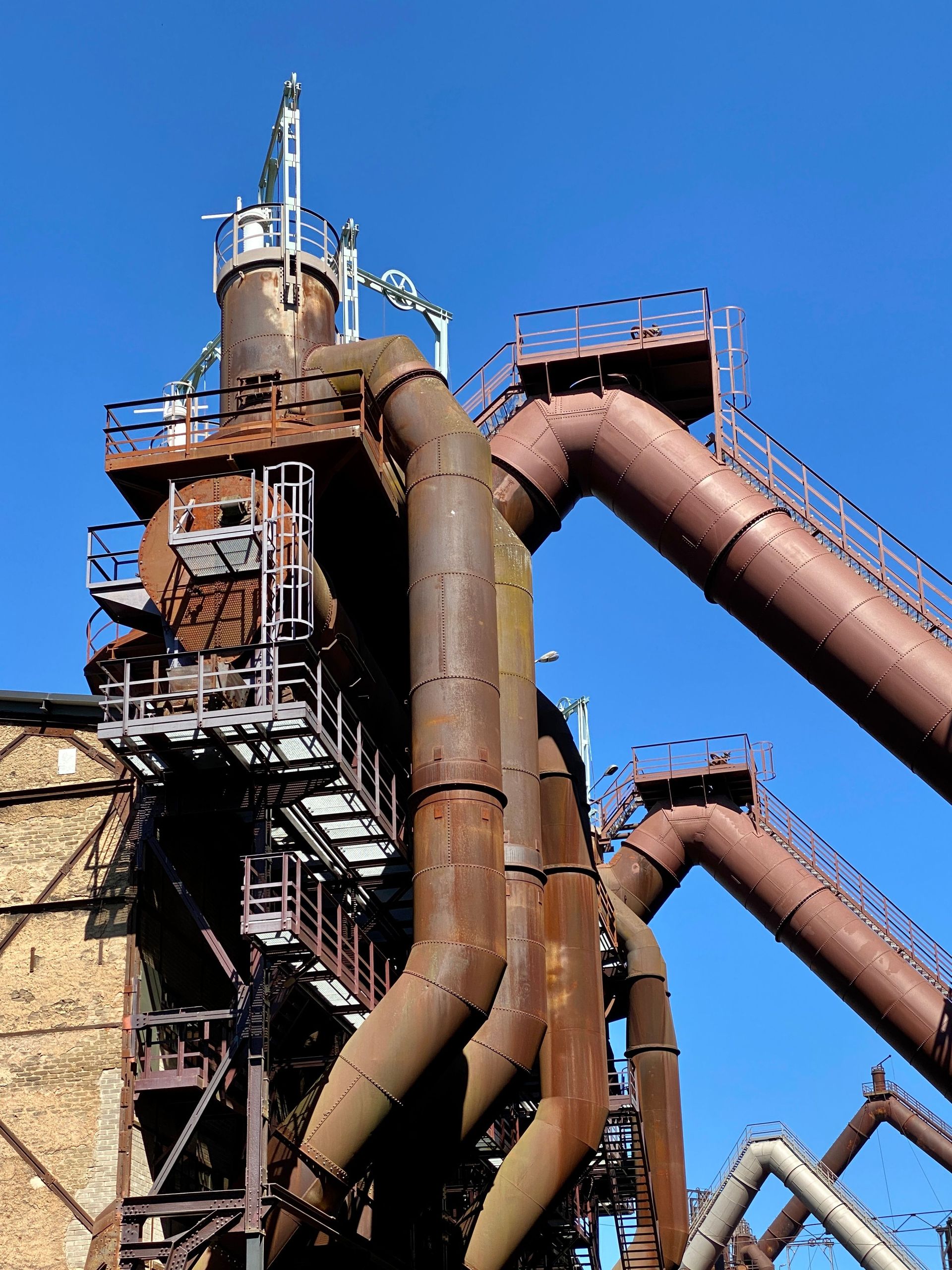 Industrial steel pipes and scaffolding against a bright blue sky