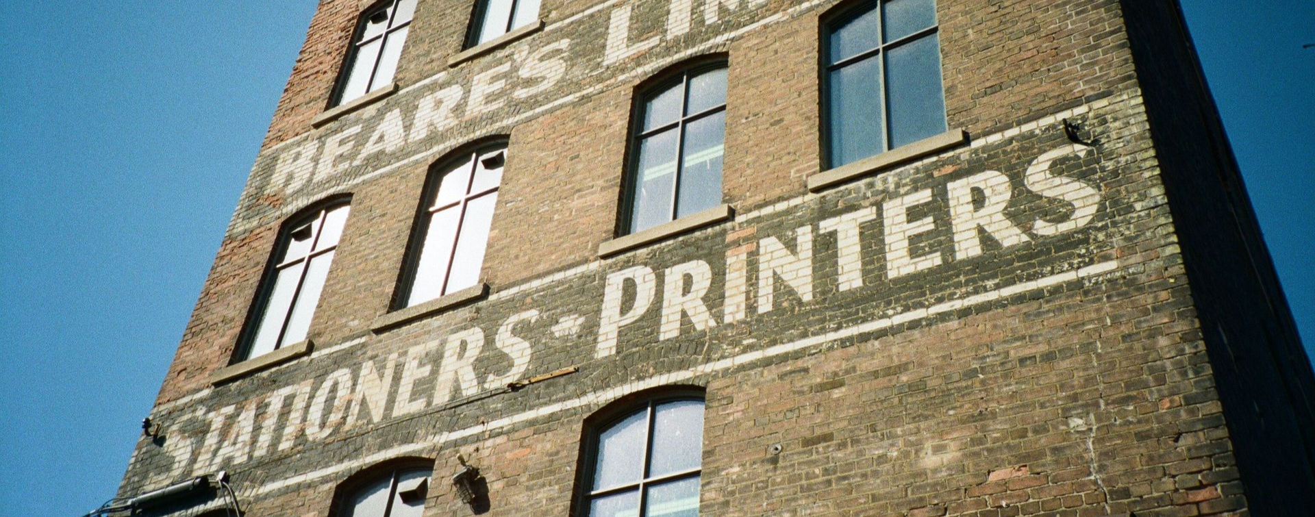 Historic brick commercial building with faded painted signage from former industrial businesses.
