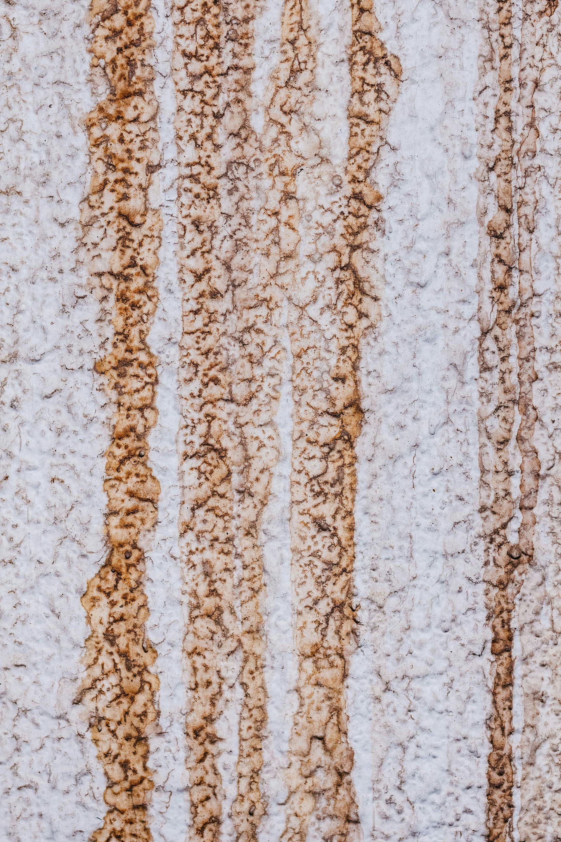 Vertical brown and tan water streaks on a white warehouse building wall