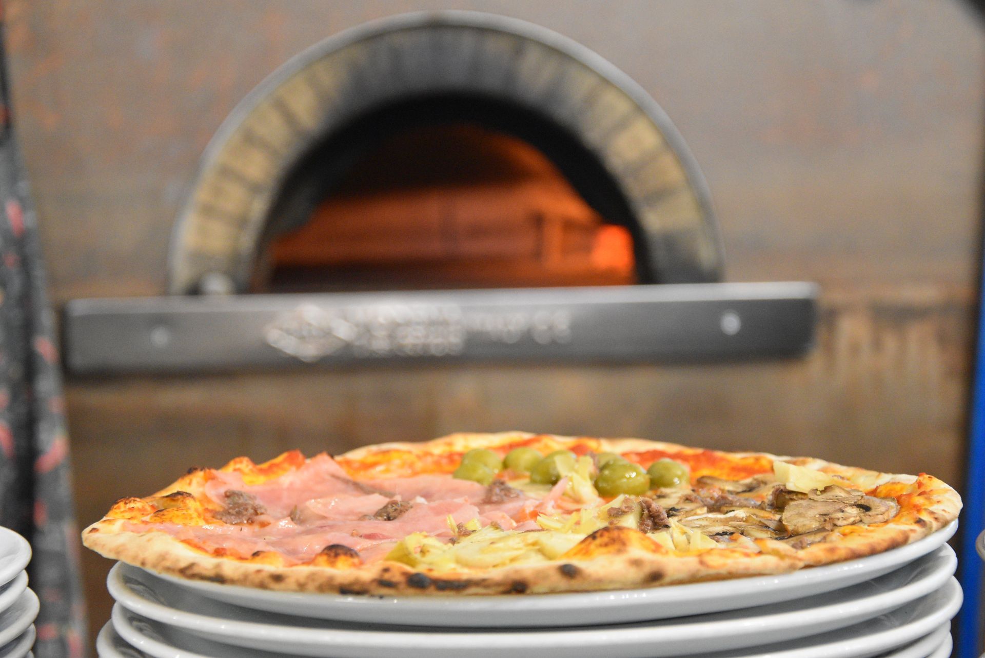 Pizza con funghi e pomodori su un piatto bianco.