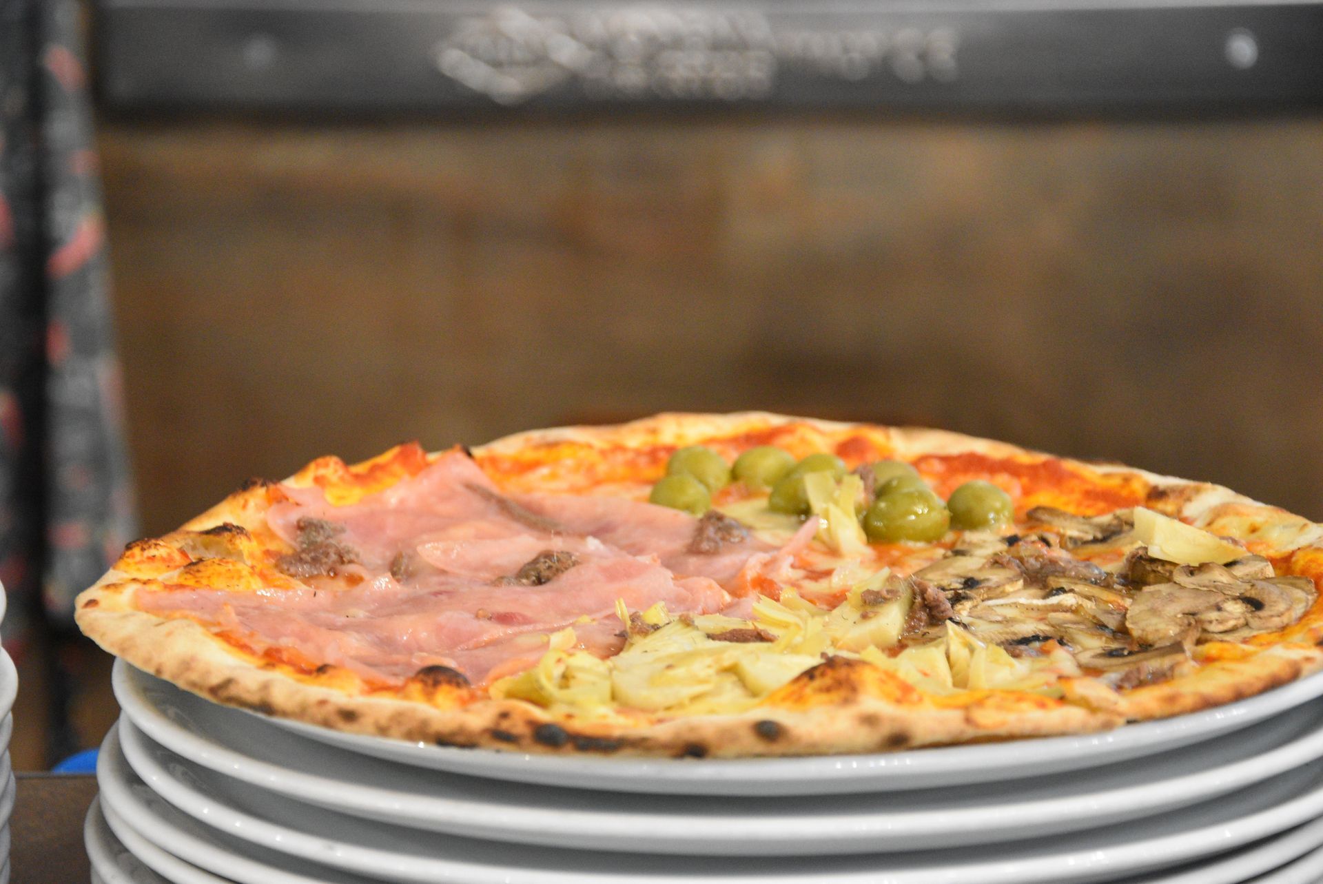 Pizza con funghi e pomodori su un piatto bianco.