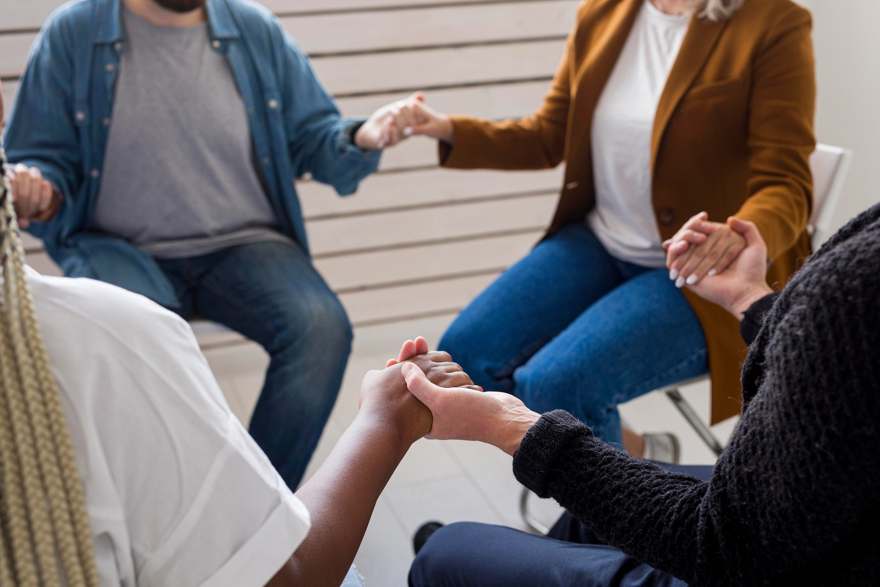 A group of people are sitting in a circle holding hands.