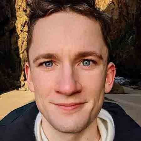 A young man with blue eyes is smiling for the camera.