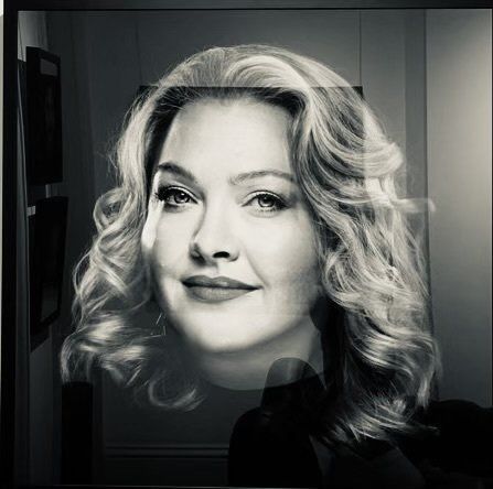 A black and white photo of our doctor with curly hair looking at the camera.