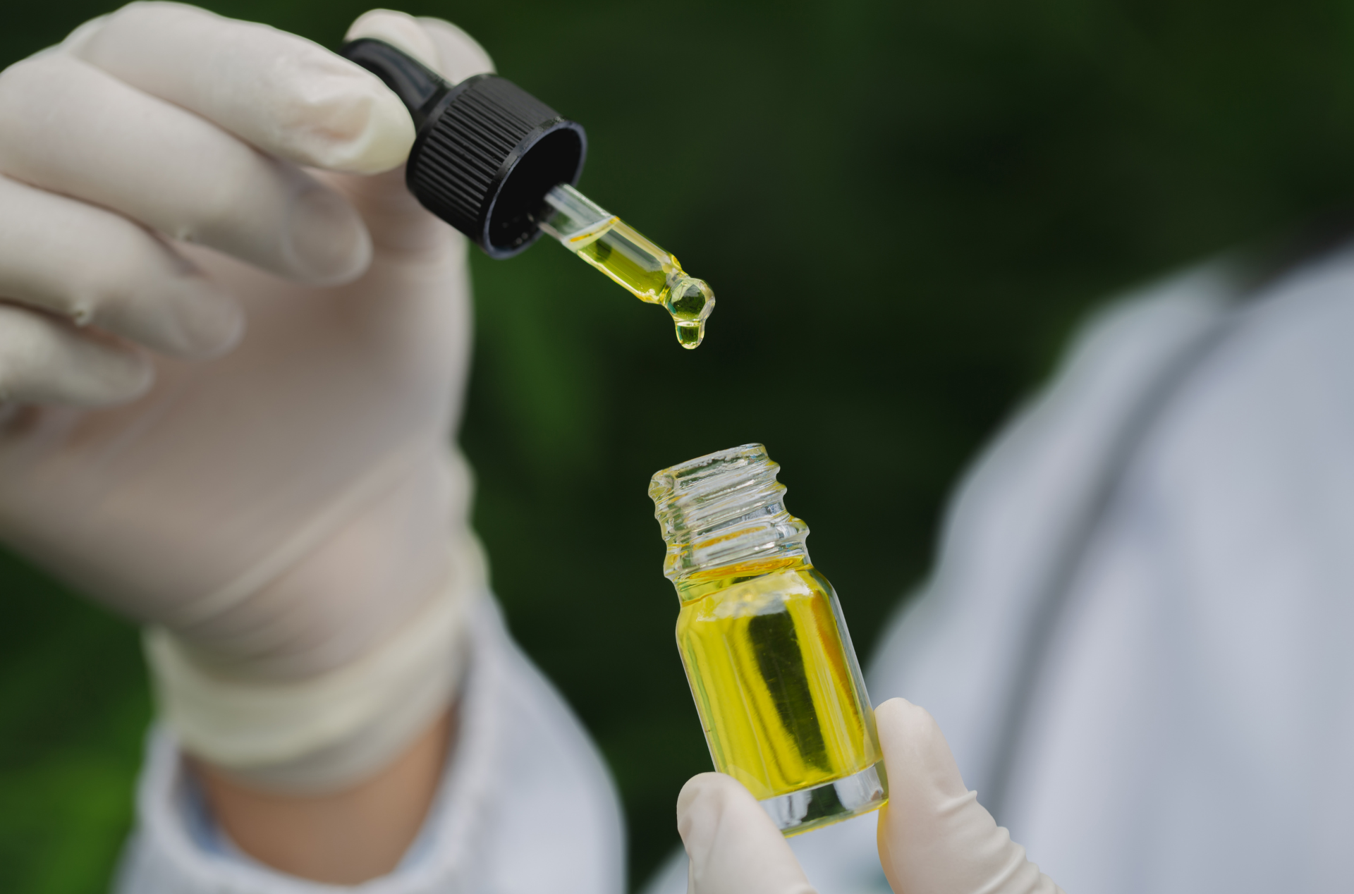 A person is holding a bottle of oil and a pipette