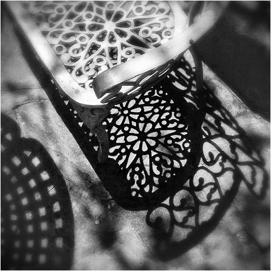 A black and white photo of a chair and its shadow
