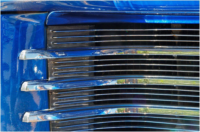 A close up of a blue car 's grille with chrome trim.