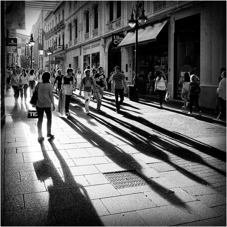 A black and white photo of people walking down a city street