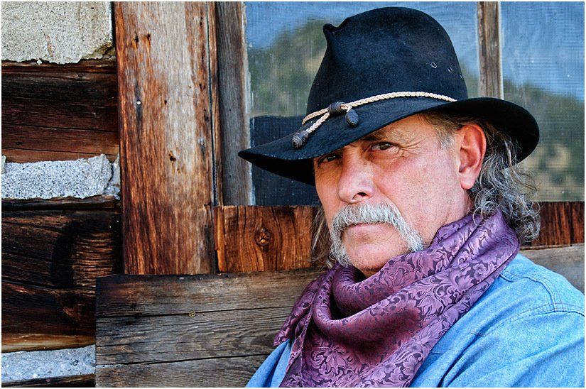 A man wearing a black hat and a purple scarf
