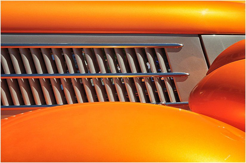 A close up of an orange car with a chrome grille